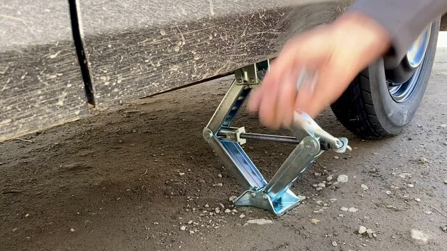 The driver of the car lifts the car on the jack to replace the tire with a new wheel. Vehicle breakdown on the road.