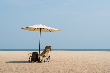 Beach chairs and umbrella by the ocean on a sunny tropical day