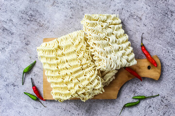 raw instant noodles on a chopping board with some chilies
