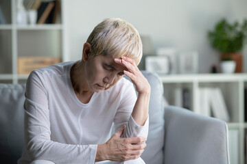 Unhappy Asian senior woman suffering from mental illness and headache. Elderly woman sits alone...