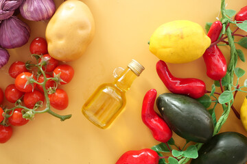 Fresh vegetables and oil arranged on a vibrant yellow background