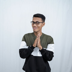 An Asian young man with glasses wearing a sweater with an expression of hiding something, mysterious or thinking evil. Isolated on white background.