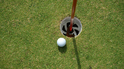 Golf ball on green grass in the evening golf course with sunshine background.