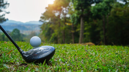 Golf clubs and golf balls on a green lawn in a beautiful golf course with morning sunshine.