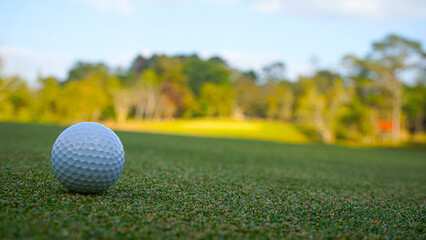 Golf ball on green grass in the evening golf course with sunshine background.