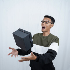 An Asian young man with glasses wearing a sweater with a surprised happy expression getting a surprise gift. Isolated on a white background.