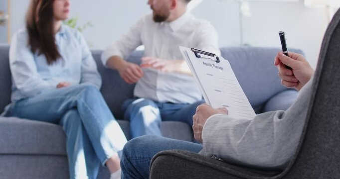 Young couple blaming each other in marriage problems sitting on couch at family therapist office during therapy session. Psychologist listening his patients trying to find solution. 4k video.