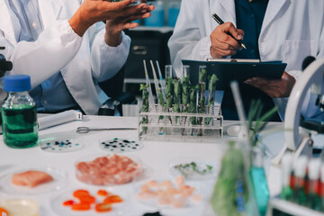 Team Asian scientists in a lab conducting food research using a microscope and lab equipment,...