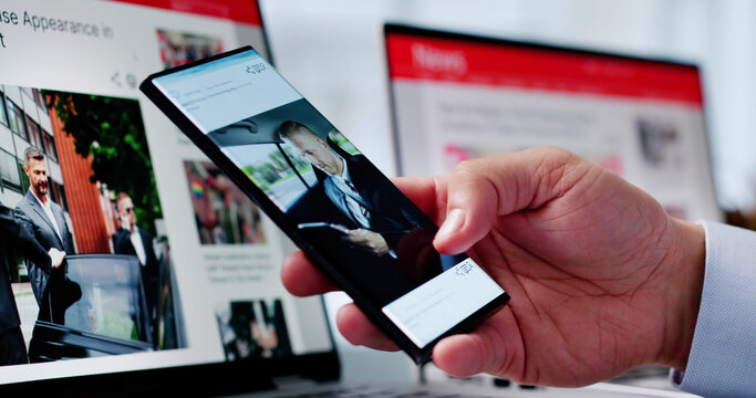 Watching Online News Article On Mobile Phone And Laptop