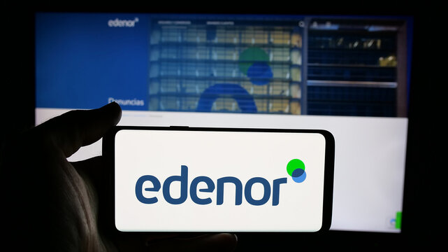 Stuttgart, Germany - 03-27-2025: Person holding cellphone with logo of Argentinian energy company Edenor S.A. on screen in front of webpage. Focus on phone display.