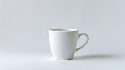 A simple, white ceramic mug with a comfortable handle sits upright against a light background, showcasing its minimalist design and smooth finish, ideal for any beverage.