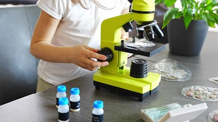 Close up view of hands of little girl preparing a sample for microscope examination. Concept of hands-on science learning and curiosity-driven exploration