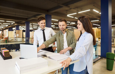 Happy family couple of client consults with a salesman before making a purchase in a hardware shop....