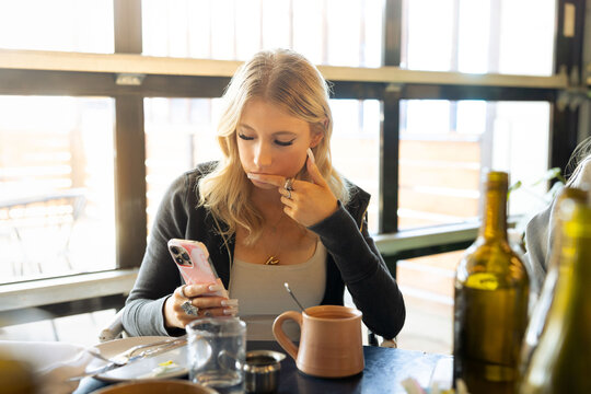 Gen Z girl with long nails looking at her phone