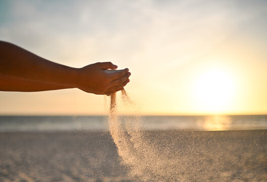Wind sweeps falling sand therough boy's hands with sunset