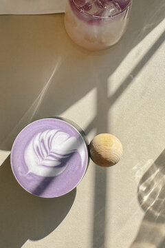 Ube latte with latte art in sunlight on neutral table