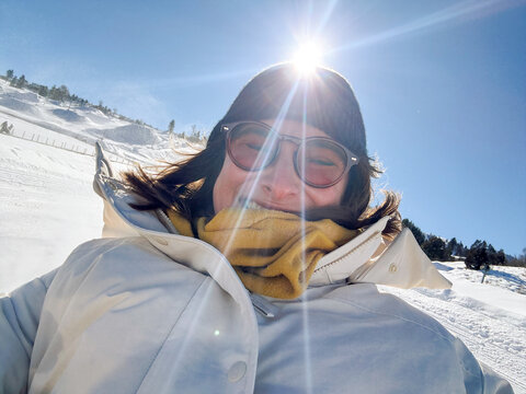 Smiling woman in her 30s tubing in snowy Utah under bright sun