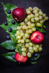 Top view of apples, blueberries and grapes with green leaves