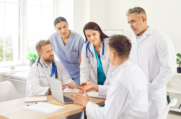 A group of doctors in a colleagues office discusses the work process, close-up. Collective...