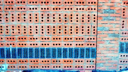 Wall made of perforated bricks arranged in alternating horizontal and vertical rows.