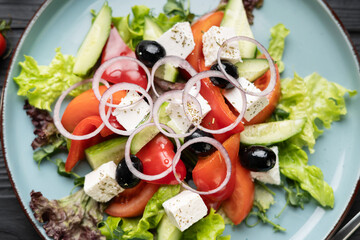 Fresh greek salad on blue plate, flat lay, top view