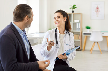 Young happy female doctor consulting adult man, health care professional talk to treat,...