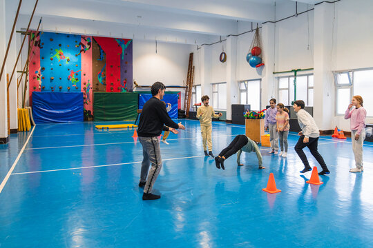 Group of elementary school children enjoying gym class with their teacher, having fun and learning new skills