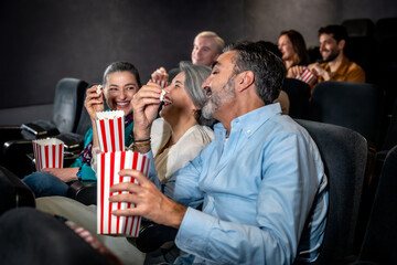 Group of friends enjoying movie and eating popcorn in cinema