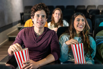 Young couple enjoying movie and eating popcorn in cinema