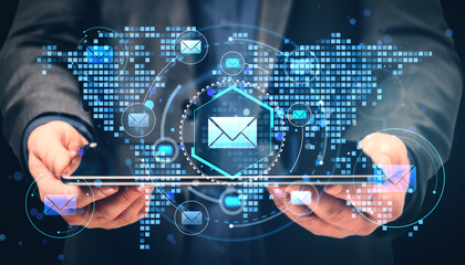 Businessperson holding tablet with digital email icons and world map background representing global communication technology concept.
