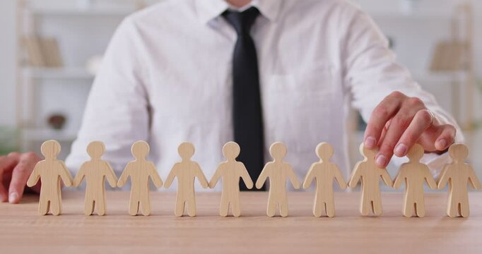 Lawyer sits at a desk with wooden figurines, symbolizing the protection of human rights and social insurance. The focus is on labor rights, social support, and the safeguarding of people lives.