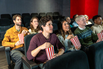 Friends watching and enjoying a movie at the cinema eating popcorn
