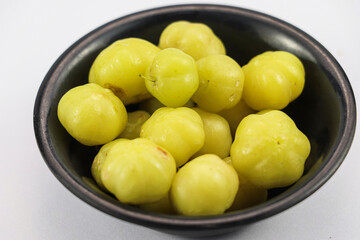 Phyllanthus acidus fruit in a black bowl, isolated