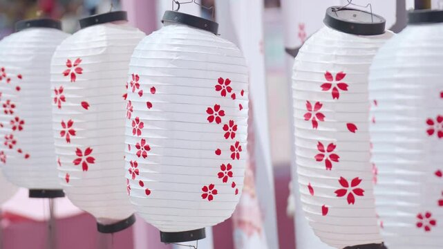 The wind blows decorative lanterns at the Sakura cherry blossom blooming Festival on a clear spring day