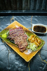 Thin slices of raw beef on a beef grill, meat starting to sear and sizzle, authentic Japanese restaurant