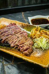 Thin slices of raw beef on a beef grill, meat starting to sear and sizzle, authentic Japanese restaurant