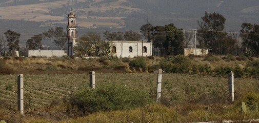 iglesia en medio del campo con arboles con fondo de colinas y tierras de cultivo