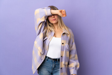Young blonde woman isolated on purple background covering eyes by hands