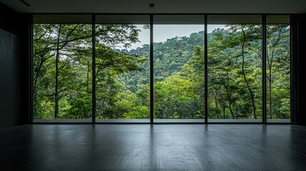 Naklejka premium Wide glass windows reveal a lush green landscape of tropical trees in a serene indoor space