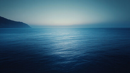 Fototapeta premium A serene view of the ocean with a distant landmass under a soft and muted sky at twilight hour