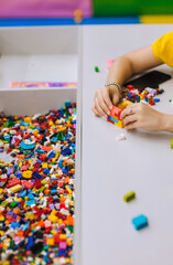 Young teenage girl assembles a construction set from plastic parts, blocks with her hands....