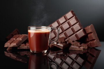 Glass mug of hot chocolate and broken bitter chocolate bar.