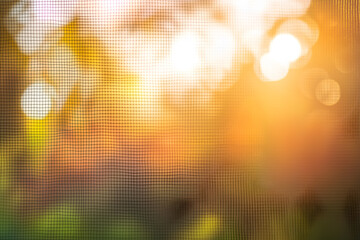 Tightly focused macro photo of insect screen pattern, with soft defocused sunlight behind, ideal for illustrating mosquito prevention