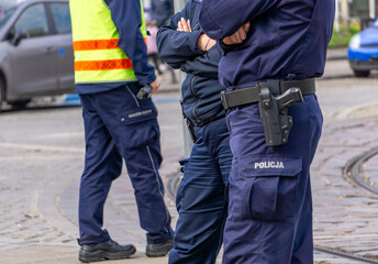 Polish police officers on duty and MPK tram traffic control workers stand by the tram tracks in Poznań. View of the tactical belts, direct coercion measures and pistols