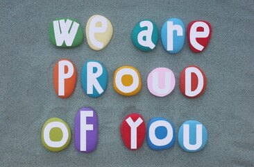We are proud of you, motivational slogan and message composed with multi colored hand painted stone...