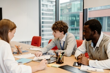 A group of diverse colleagues, including a young White woman, and man with curly hair, and an adult...