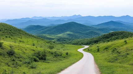 Fototapeta premium A winding road curves through lush green hills and mountains. The landscape features rolling hills, abundant greenery, and a clear sky. The image is high-resolution, showcasing vibrant colors and exc