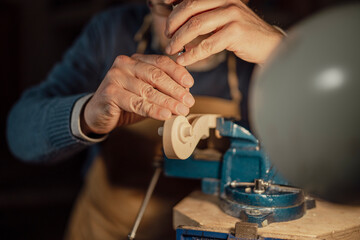Skilled luthier carefully carving violin scroll with traditional hand tools, revealing intricate woodworking expertise in classic workshop setting