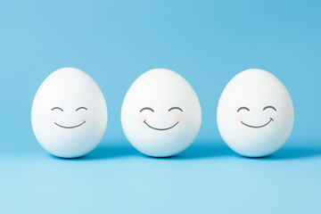 Trio of white eggs with smiling faces on blue background, minimal cheerful expression concept in pastel tones