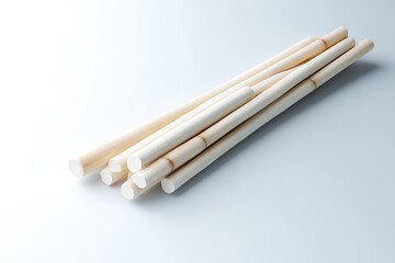 Light beige cylindrical sticks, clustered and bundled, lie on a plain white surface.  The sticks have a slightly rough, natural texture with horizontal light brown lines